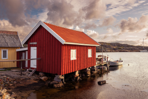 Die bunten Holzhäuser im Hafen von Björholmen auf der Insel Tjörn in den Schären der Westküste von Schweden in der Morgensonne