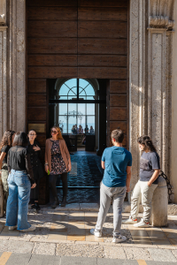 Junge Männer und Frauen stehen am Eingang eines Gebäudes der Universität in der Altstadt von Assisi und reden miteinander, Umbrien, Italien