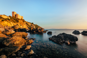 Die Burg Rocca Aldobrandesca an der Felsenküste der Maremma in Talamone im goldenen Sonnenuntergang, Toskana, Italien
