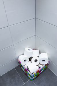 Ein Haufen Klorollen in einem bunten Korb in der Ecke einer Toilette