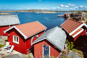 Typisch rote Schwedenhäuser vor dem Badeplatz in Stocken in den Schären der Westküste von Schweden in der Sommersonne